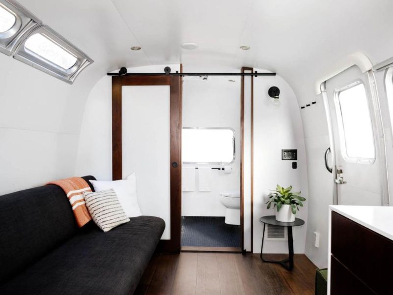 Lounge area inside an Airstream trailer leading to a compact bathroom at AutoCamp Yosemite in Midpines CA.