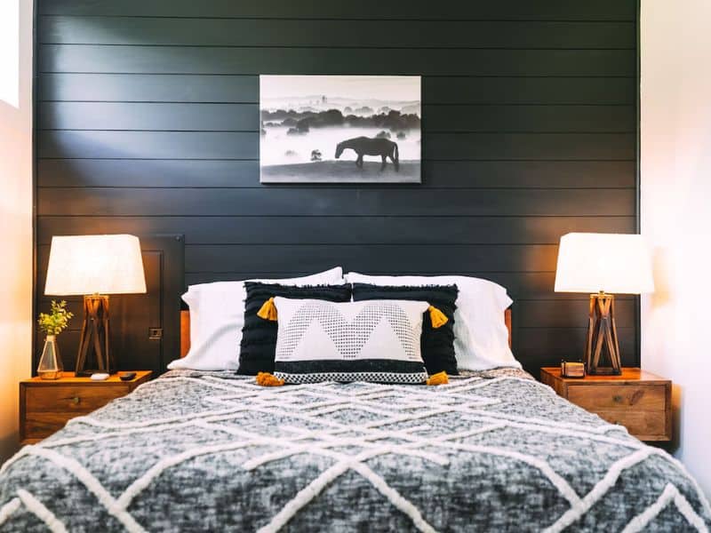 Chic bedroom in The Silo Tiny House with a black accent wall, horse canvas art, and stylish bedding with mustard accents. Hocking Hills, OH.