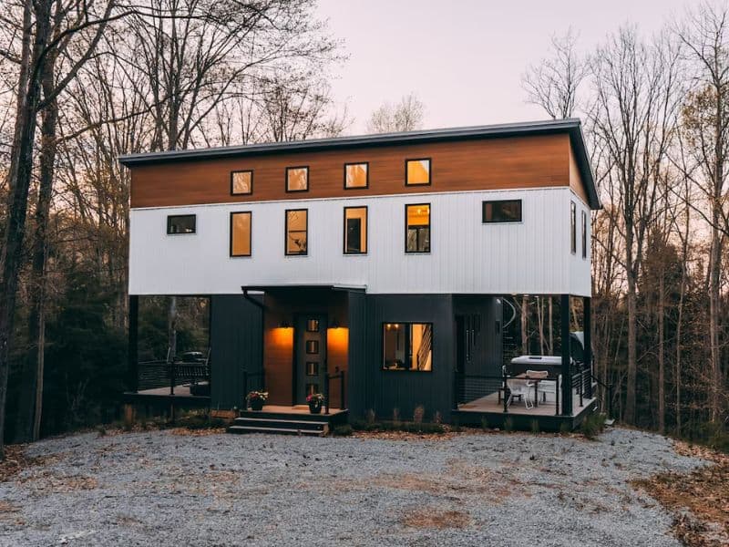 Exterior view of The Rohe Block at dusk, displaying the contemporary two-story design of this Hocking Hills container cabin with warm interior lighting and a welcoming entrance.