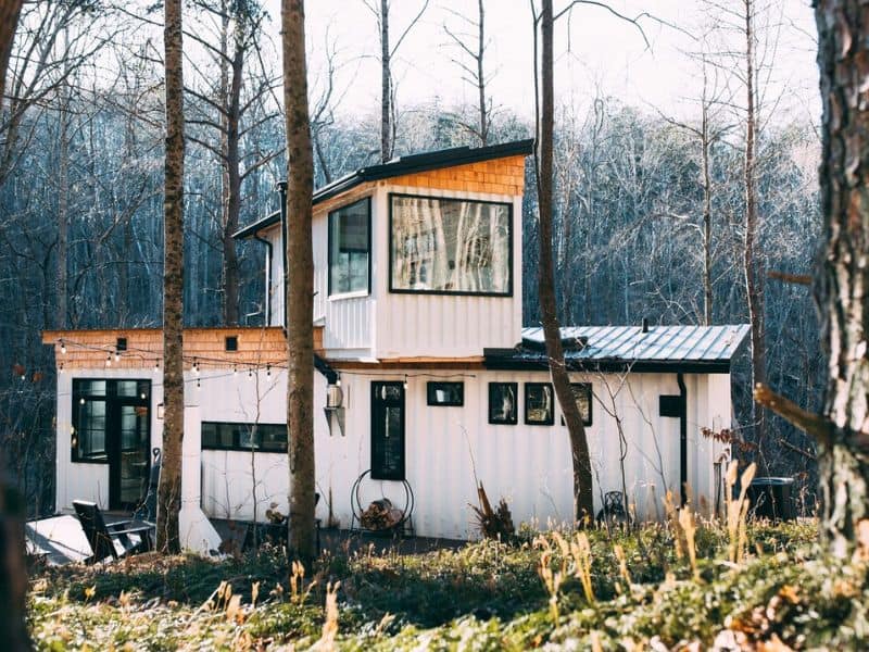 The Boho Box Hop nestled among trees, a two-story Hocking Hills container cabin with a blend of modern and rustic design elements.