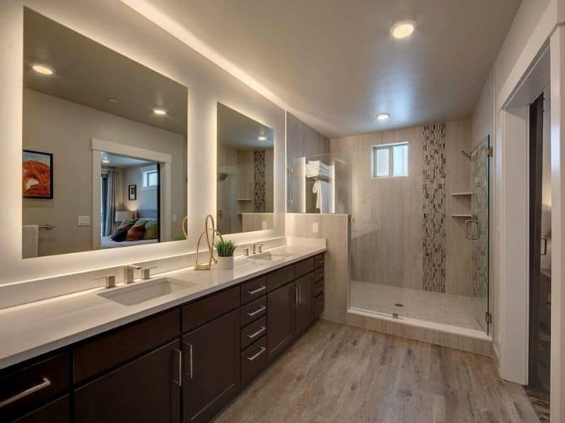 Spacious bathroom with dual sink vanity, large mirror, and a walk-in shower, decorated in light tones and wood finishes.